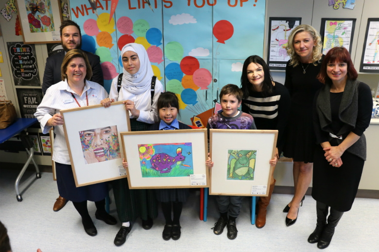 Group of children and adults holding artworks