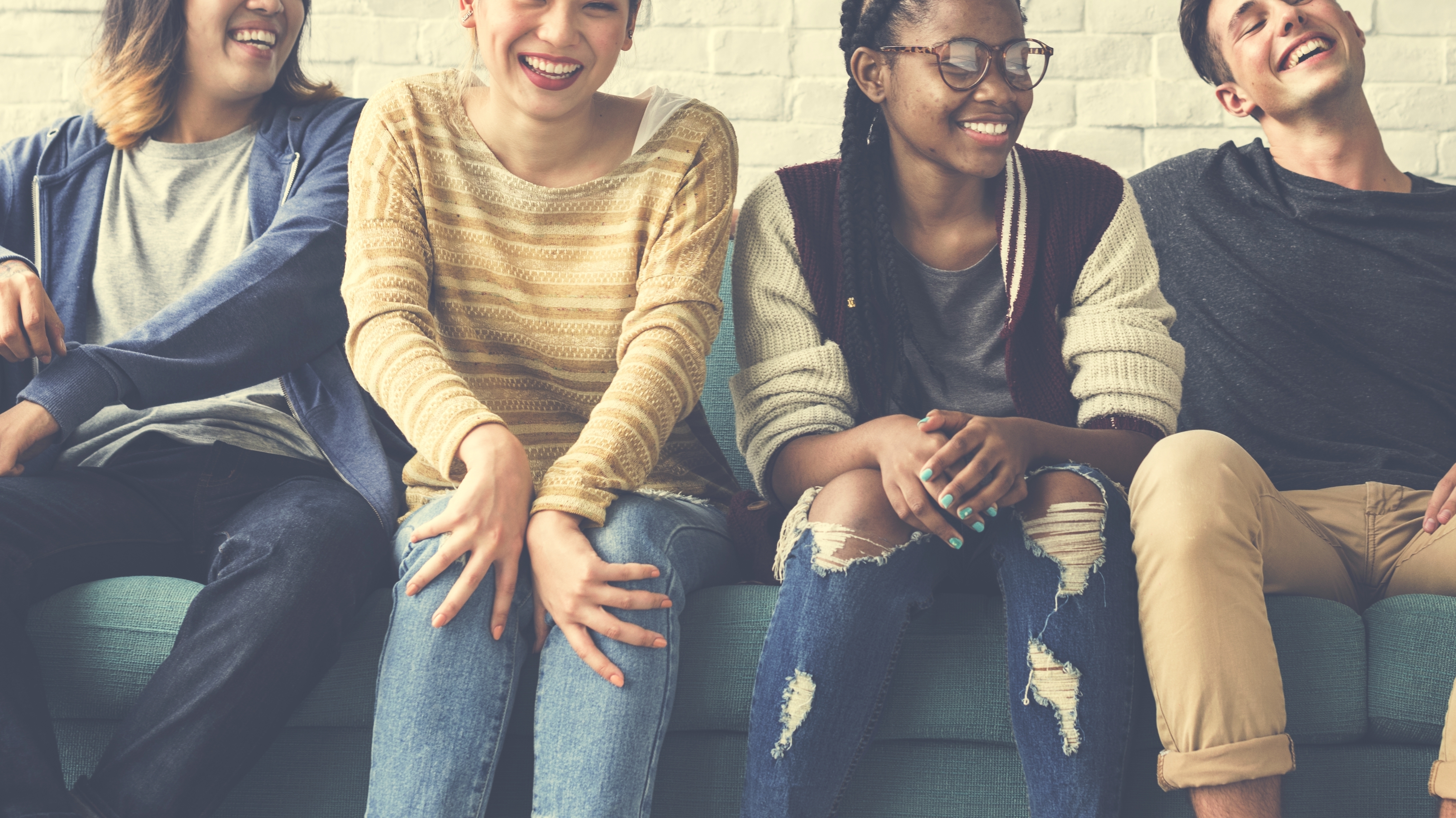 A group of four young people sitting on a couch laughing