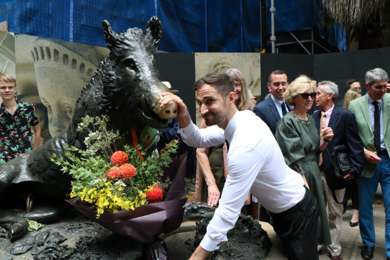 Man leaning on statue of pig