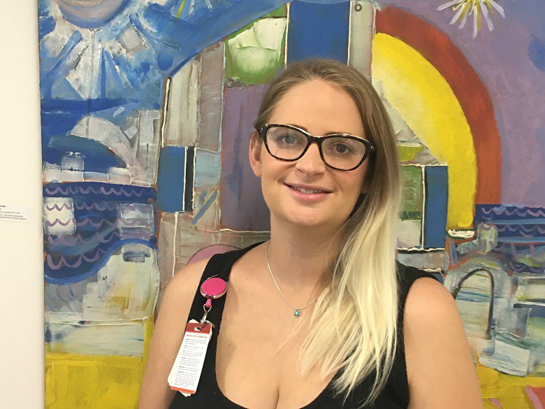 Woman in glasses in front of mural 