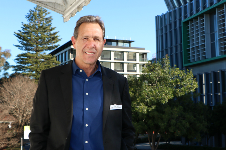 Man standing on balcony with trees in background