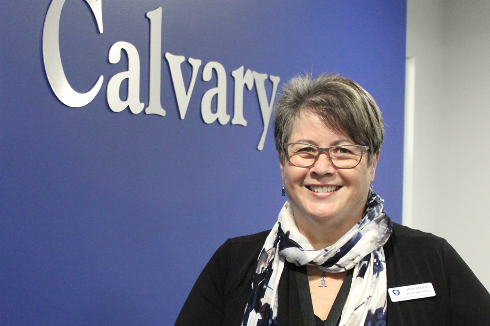 Lady in front of purple Calvary sign