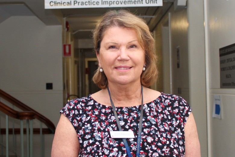 Woman in hallway with sign saying Clinical Practice Improvement Unit