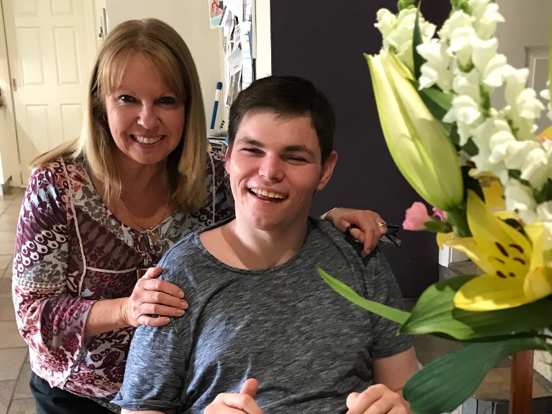 Woman standing behind man with disability