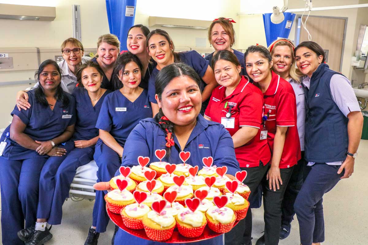 Staff holding love heart cupcakes  