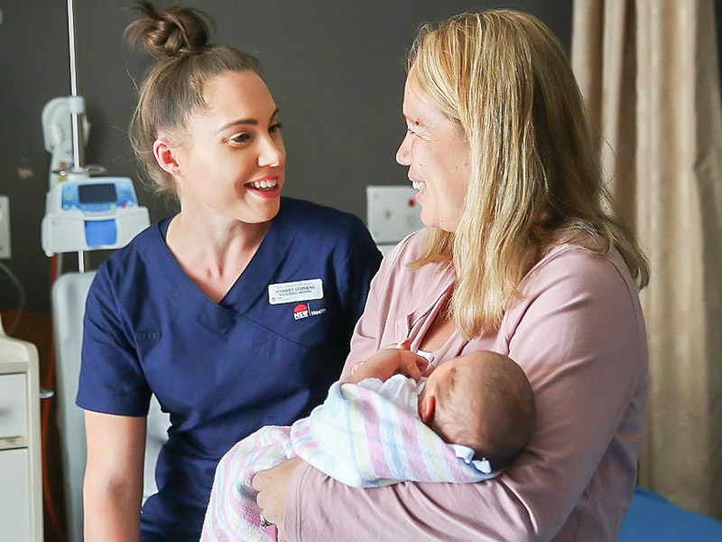 Midwife Harriet Stephens and new mum Joanna Mansour holding her new bundle of joy