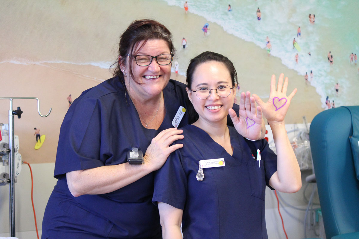 Staff members smiling showing their heart on their hand 