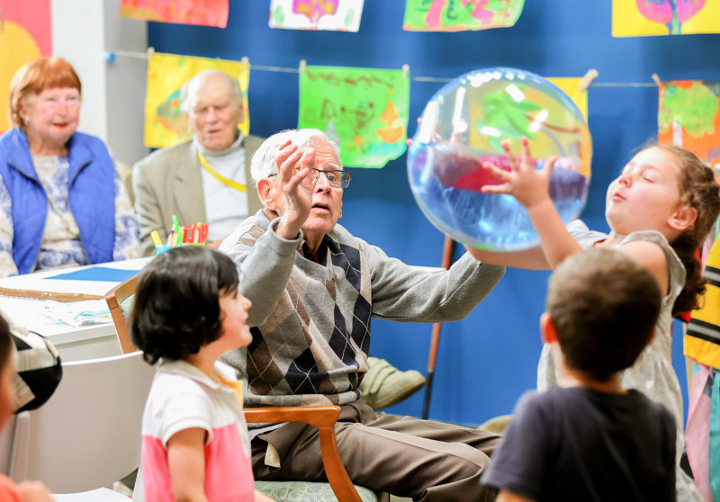 An elderly man and children playing with a ball 