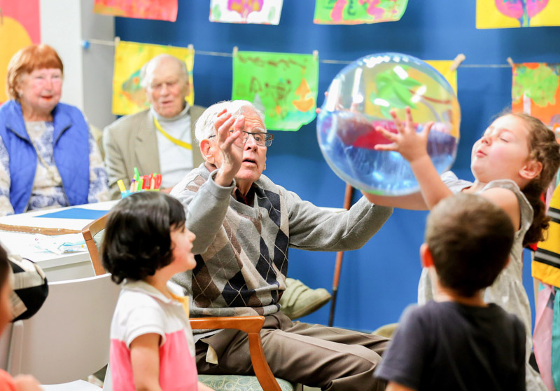 An elderly man and children playing with a ball