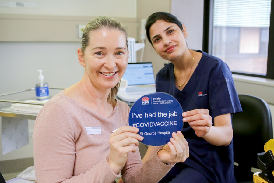 Staff holding up a sign saying they have been vaccinated
