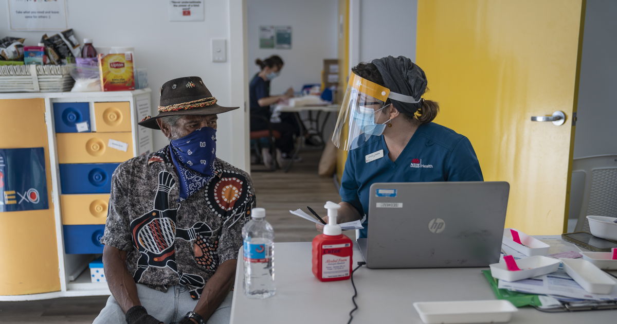 Man speaking with staff member about vaccination