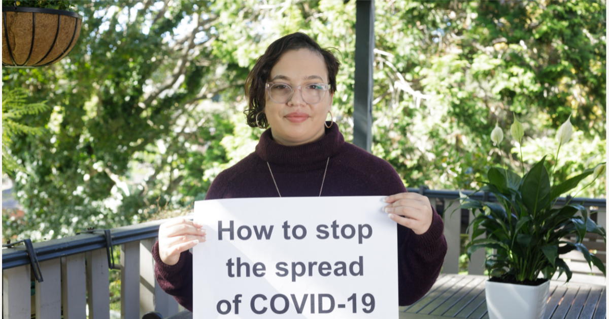 Female holding a sign, saying "How to stop the spread of COVID-19"