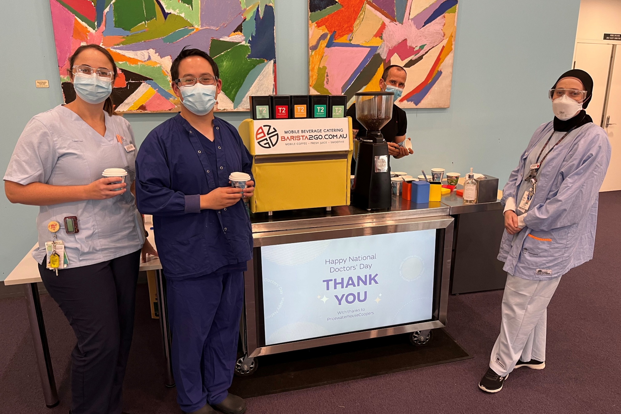 Staff enjoying a coffee in front of the coffee cart