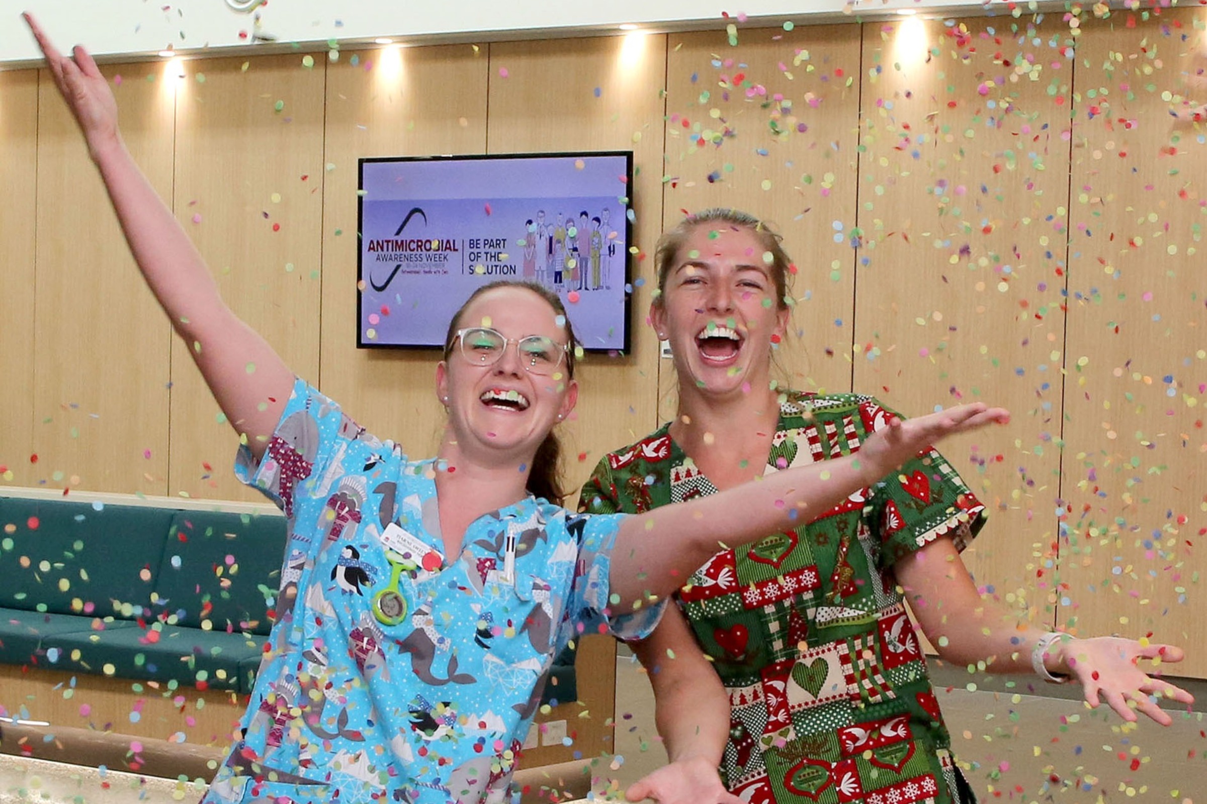Staff wearing patterned scrubs throwing confetti in the air