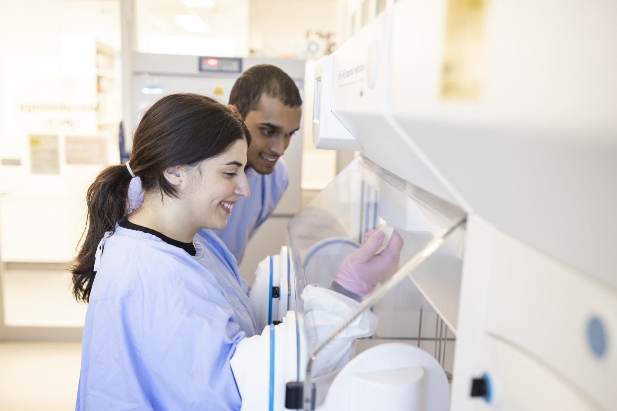 Two researchers working at a machine to analyse a sample.