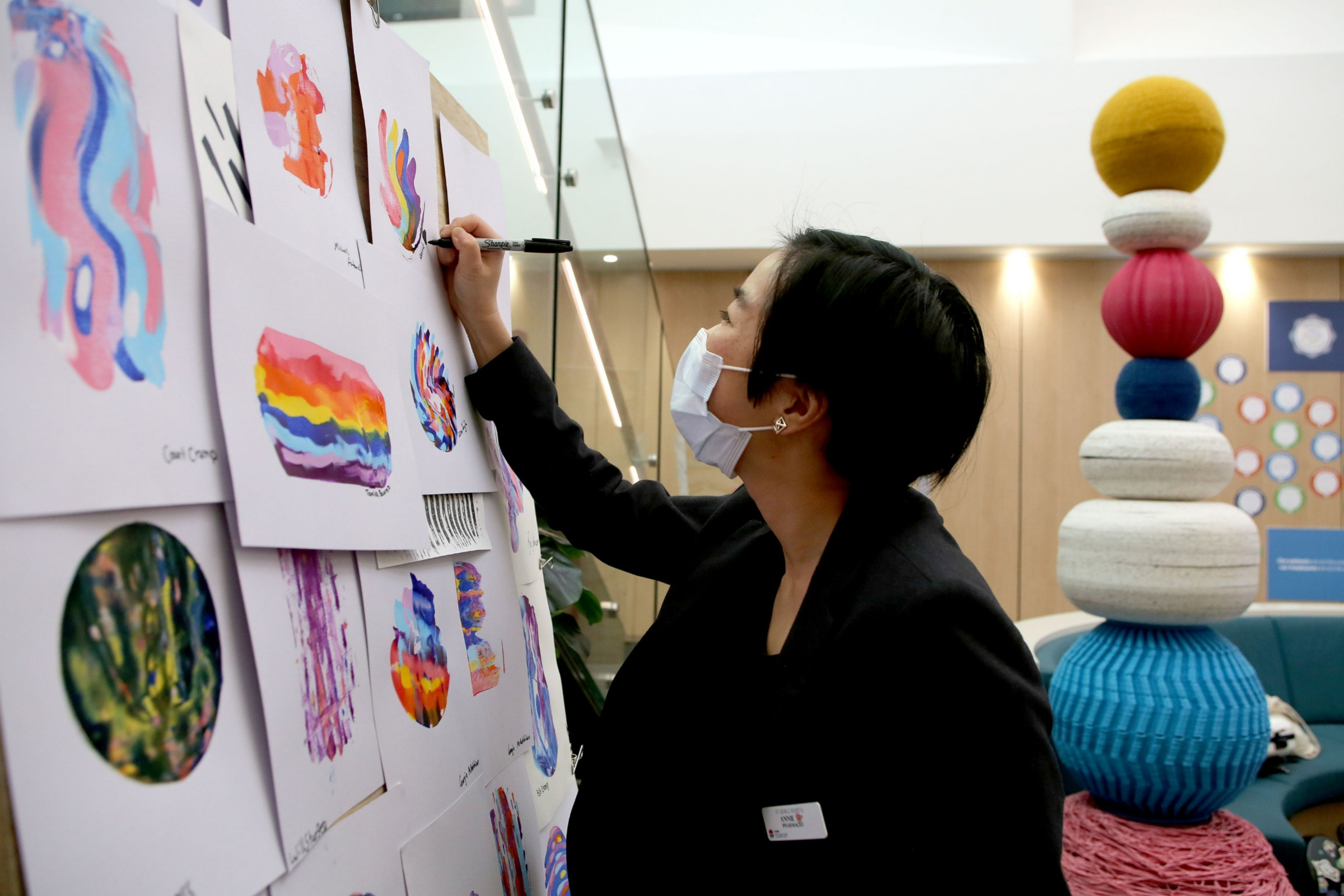 Staff member signs an artwork on the wall as part of the Festival of Care