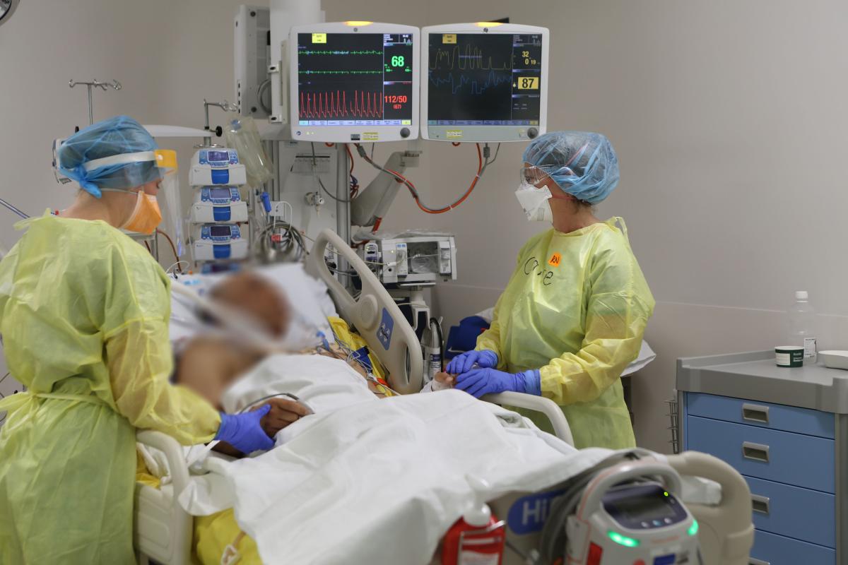 Critically ill patient in intensive care being treated by two health professionals