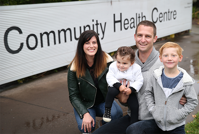 Family of four in front of Community Health sign