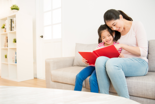 An Asian mother teaching reading a book with her child.