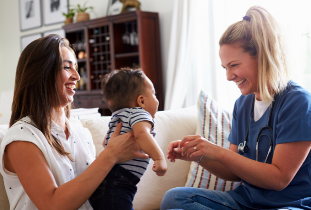 A mother and child smiling with a health professional at a home visit