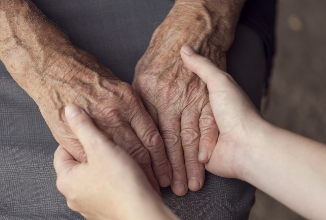 Young person's hands holding older person's hands