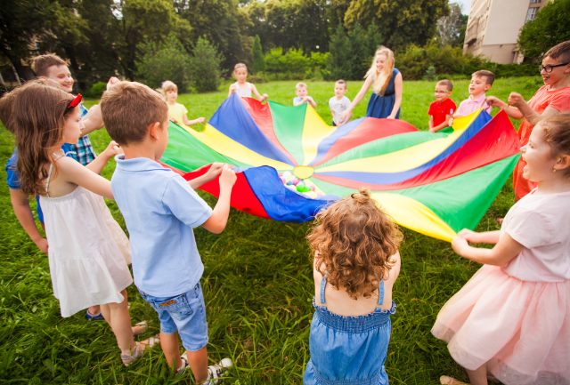 A group of children and teacher holding a circle parachute