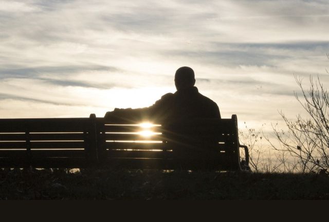 Silhouette of a man sitting on a park bench