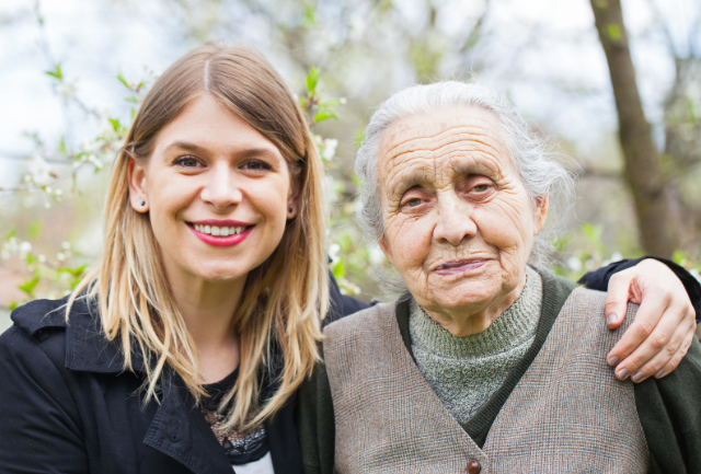 A younger woman with her arm caringly placed around an older person