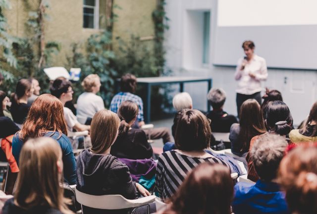 Female speaker giving presentation in lecture hall.