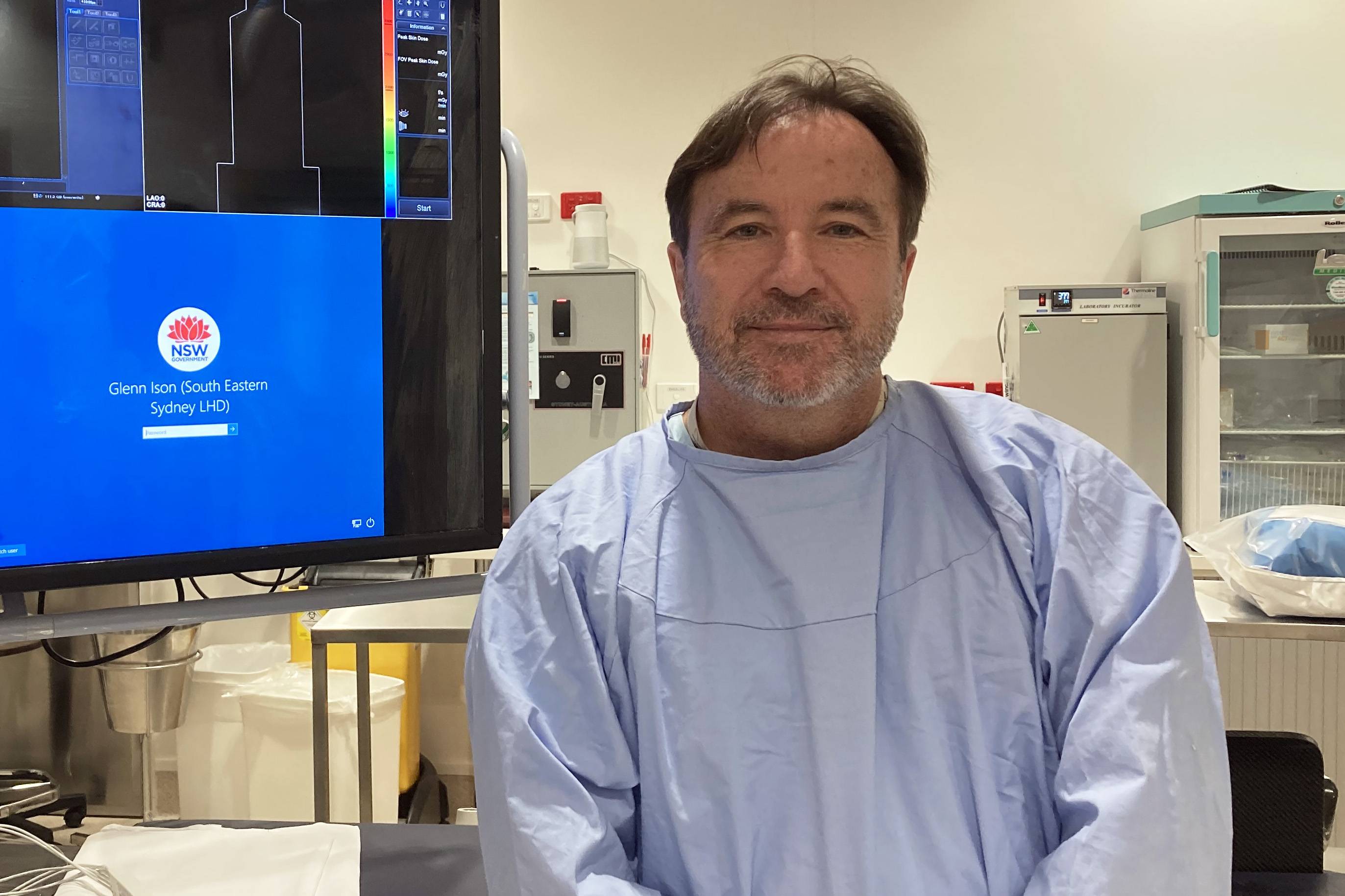 Man in surgical attire in front of screen