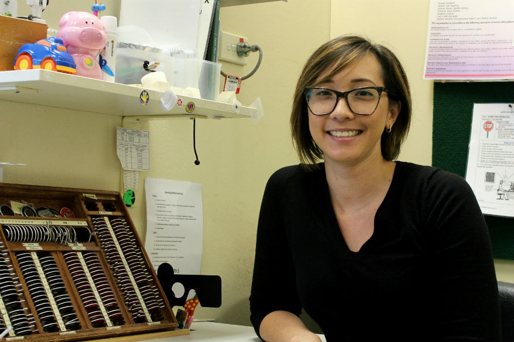 Melanie Lai sitting in office with optical equipment