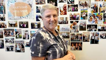 Julie Cosgrove standing in front of a wall of photos