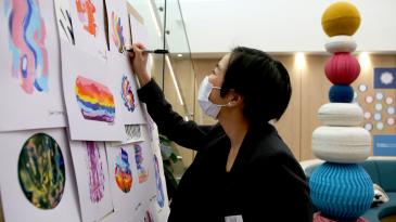 Staff member signs an artwork on the wall as part of the Festival of Care